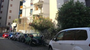 A multi-story residential building with balconies, parked cars, and a clear blue sky. - Vatican Central Suites (Rome)