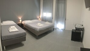 A modern hotel room with two single beds, a small table with a tray, and a TV mounted on the wall. - Vatican Central Suites (Rome)