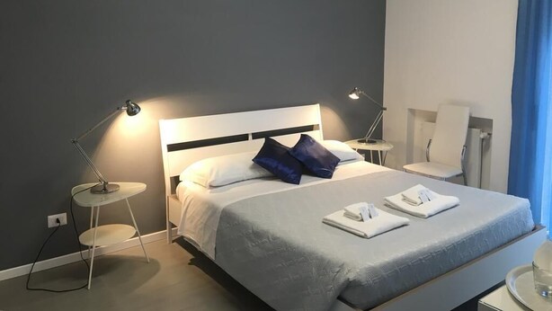A modern hotel room with a large bed, two bedside tables, and a small round table. - Vatican Central Suites (Rome)
