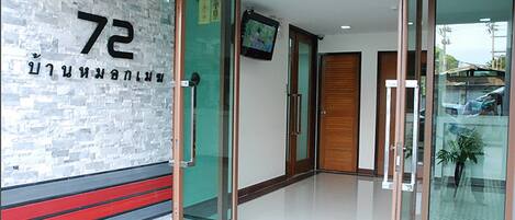 A hotel entrance with a glass door, a number '72' sign, and a television on the wall.