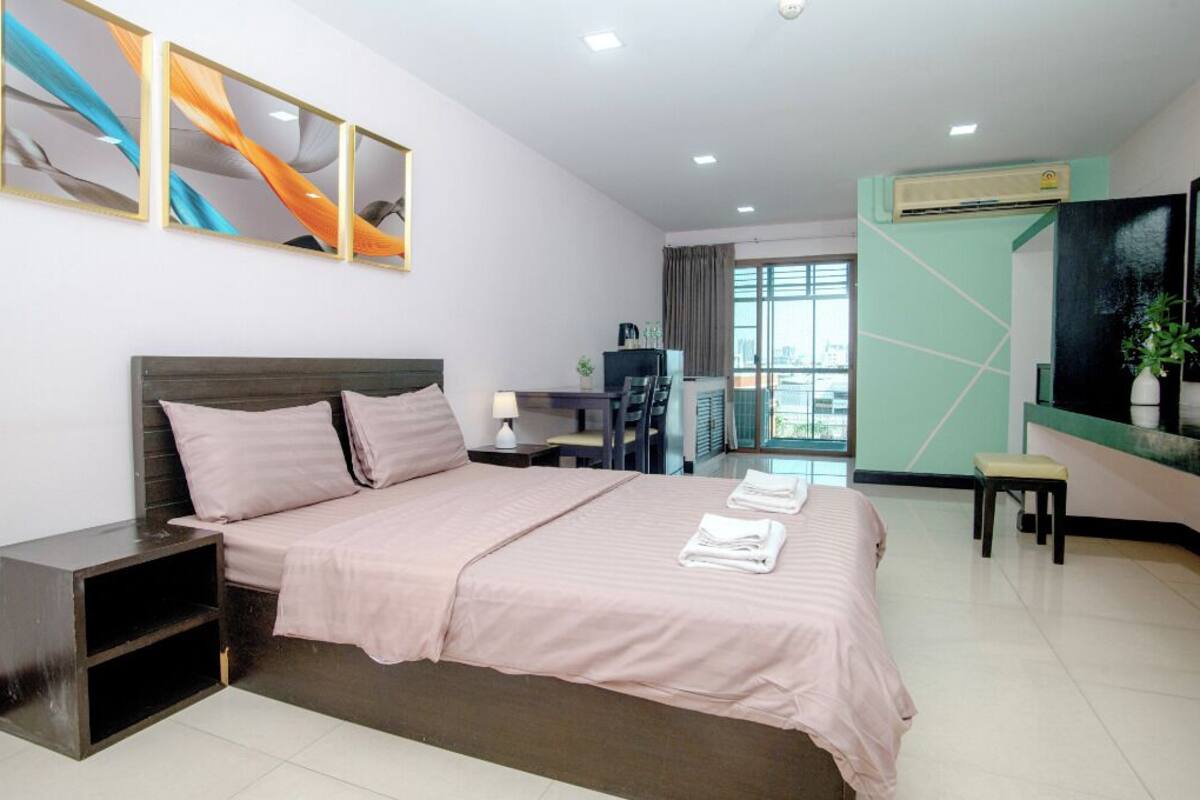 A modern hotel room with a large bed, a desk, and a TV.