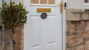 A white door with a window, a mailbox, and a stone wall.