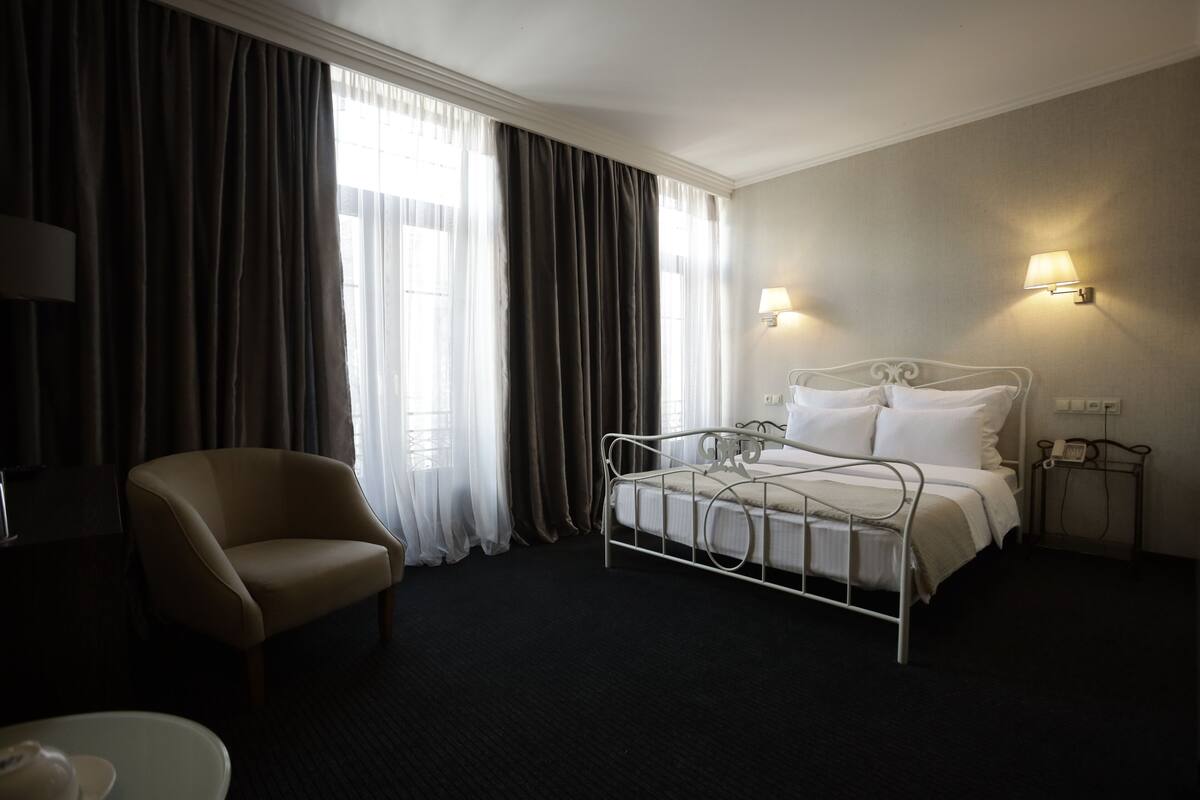A hotel room with a single bed, a chair, and two bedside lamps.