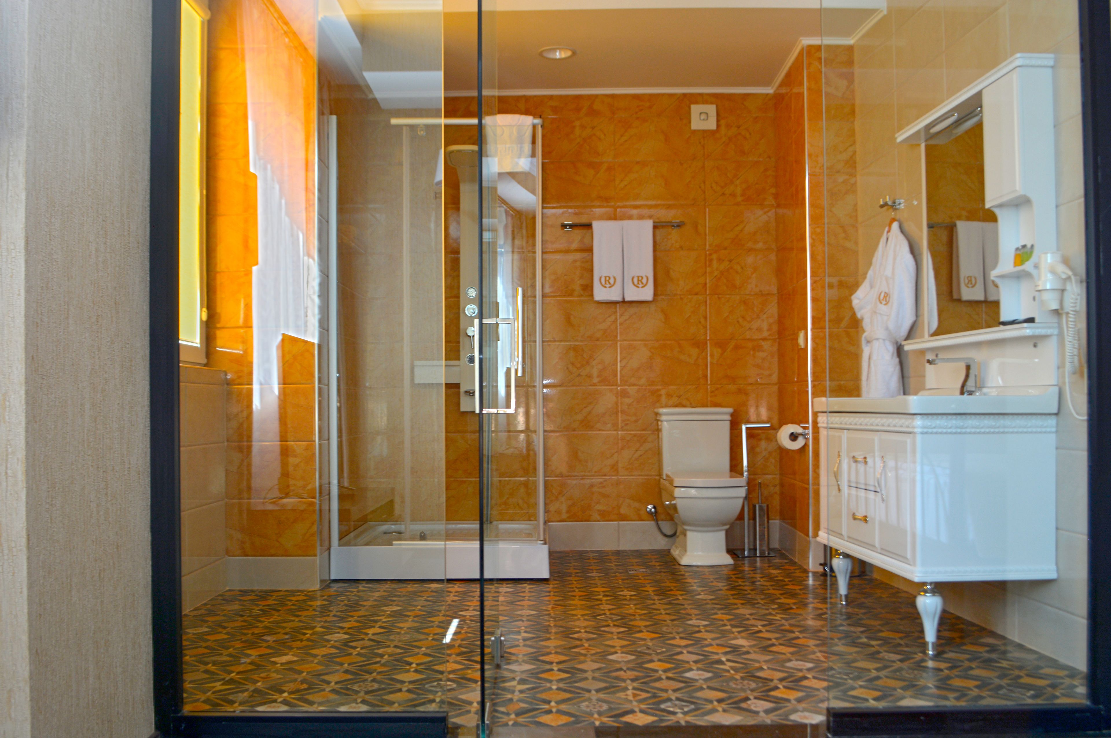 A bathroom with a glass shower enclosure, a toilet, and a vanity with a mirror.