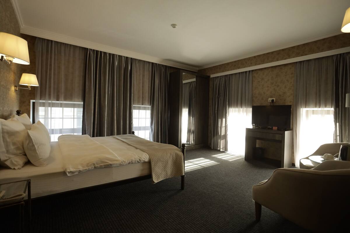 A hotel room with a bed, a TV, a desk, and a chair.