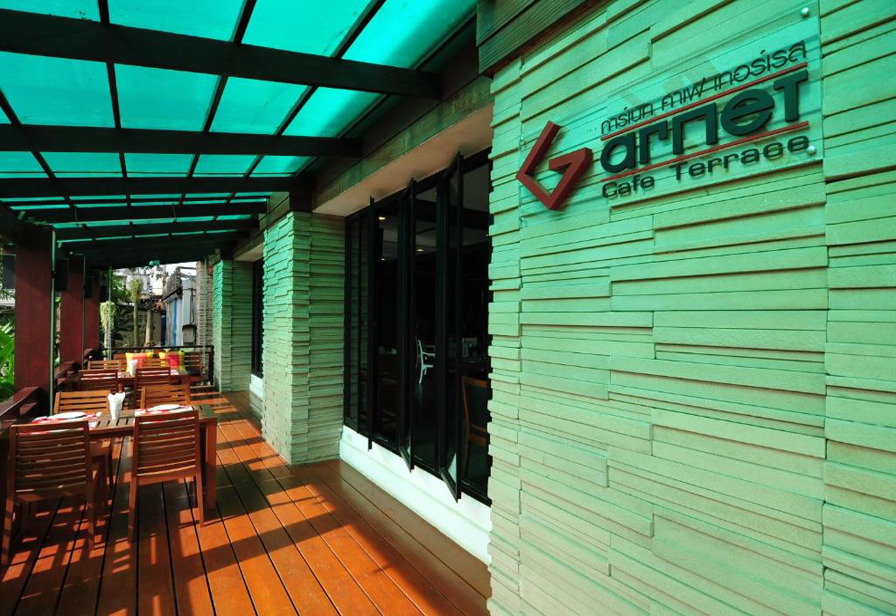 A cafe terrace with outdoor seating and a green awning.