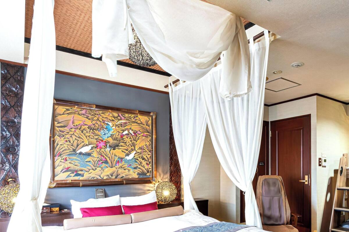 A bedroom with a canopy bed, a mural, a bunk bed, and a door.