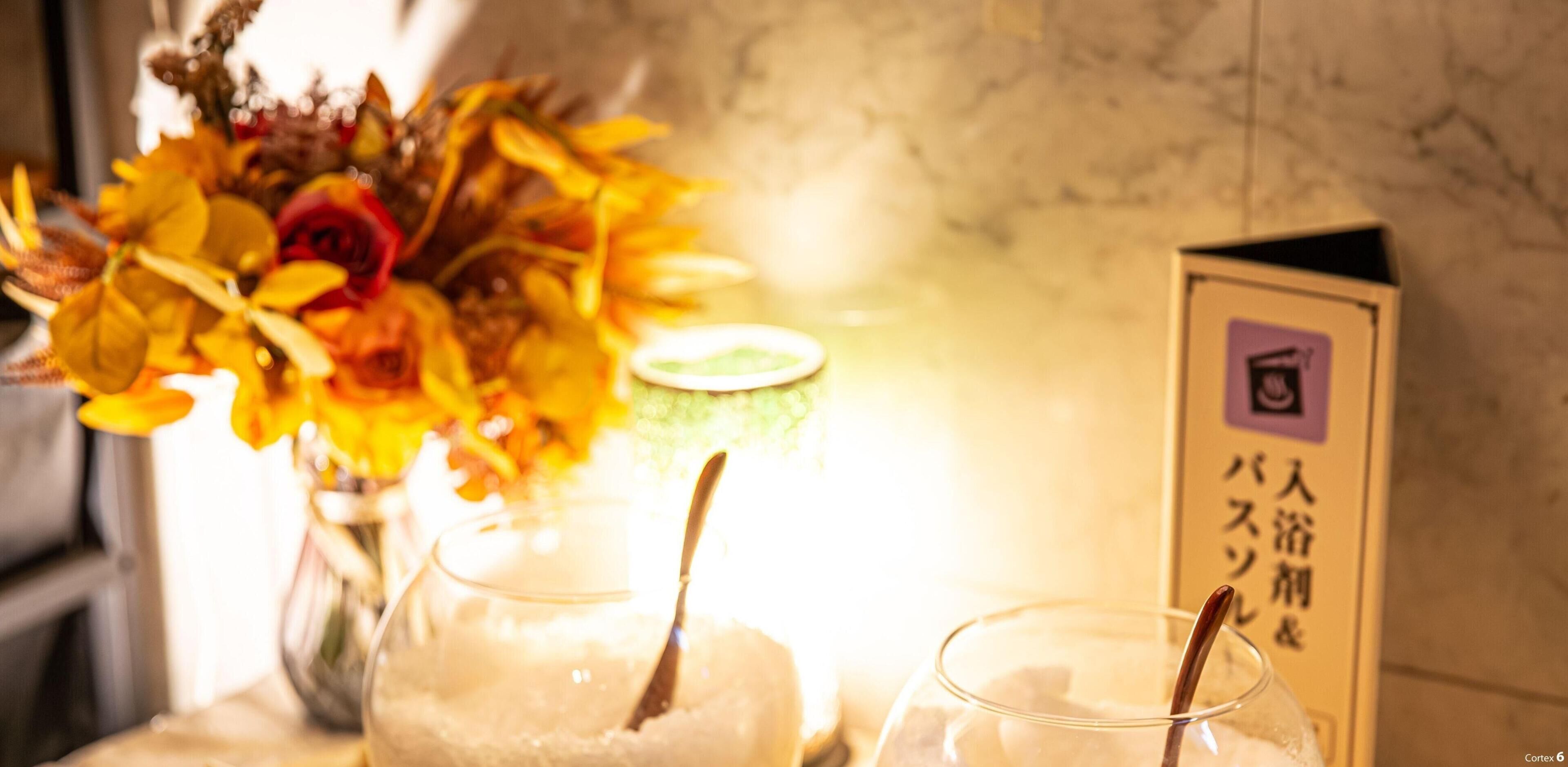 Una mesa con un jarrón de flores, dos vasos con pajitas y un letrero con texto en japonés.
