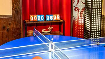 Ein Pingpongtisch mit rotem Vorhang im Hintergrund und einer Uhr, die 06:05 anzeigt.
