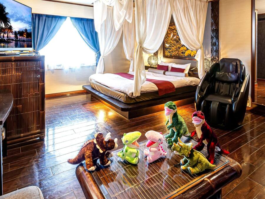 Ein Hotelzimmer mit Bett, Massagesessel, Schreibtisch und einem fenster mit Vorhängen.