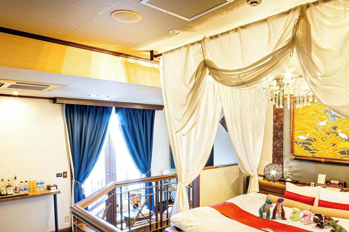 A hotel room with a bed, a nightstand, a chandelier, and a painting on the wall.