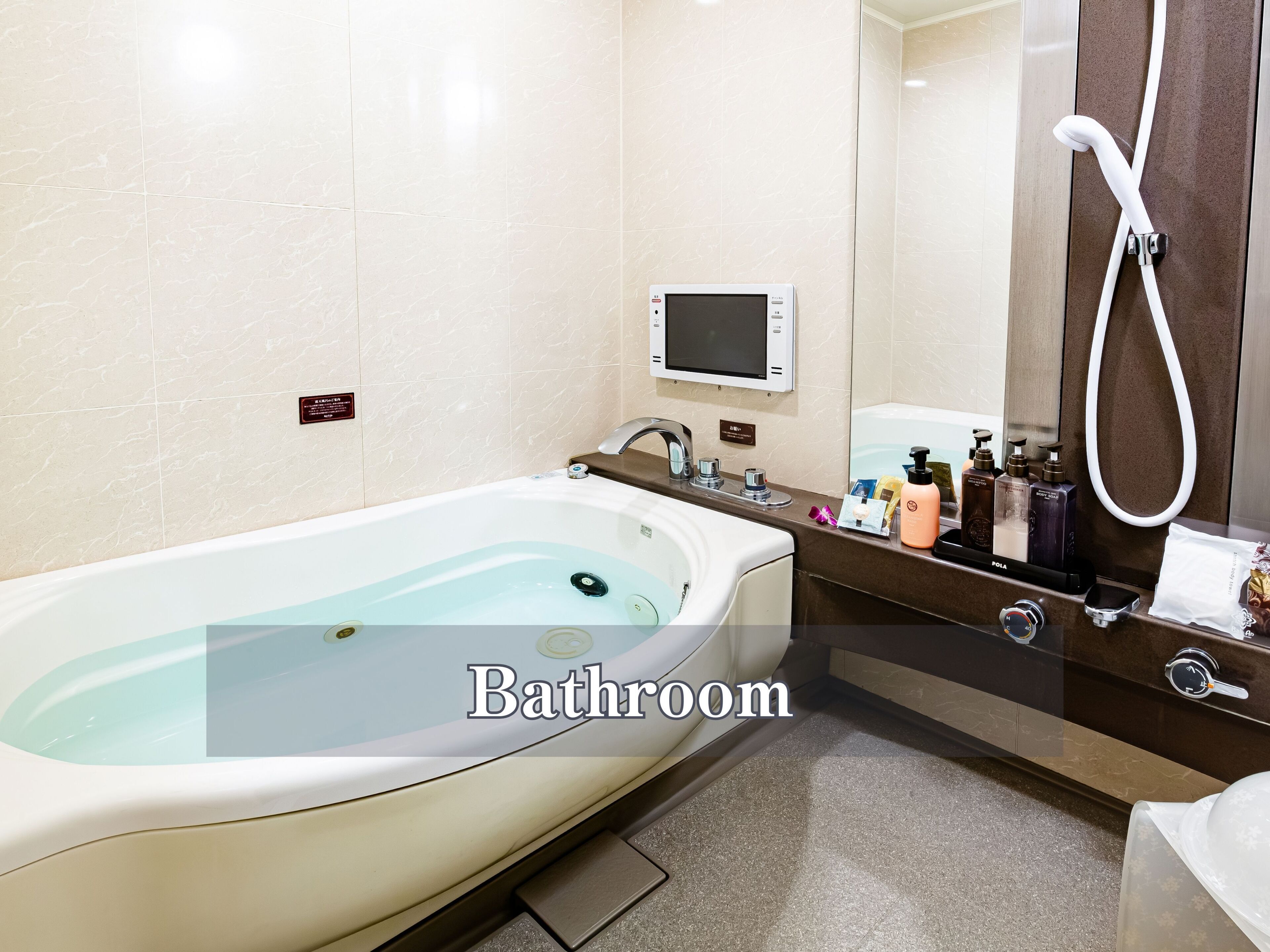 Une salle de bain équipée d’une baignoire, d’un panneau de commande numérique, d’un miroir et d’articles de toilette.