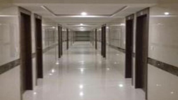 Un pasillo largo y estrecho con piso brillante y reflectante, y puertas a ambos lados.