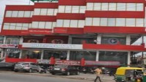 Un edificio de varios pisos con fachada roja y blanca, que muestra un letrero que dice 'Motel Delux Plaza' y un letrero de 'Hotel' debajo.