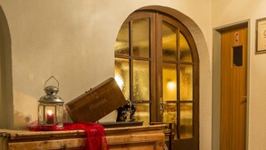 Un pasillo con un banco de madera, un farol y una puerta con un certificado enmarcado.