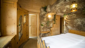 Una habitación de madera con una cama, un banco y una puerta.