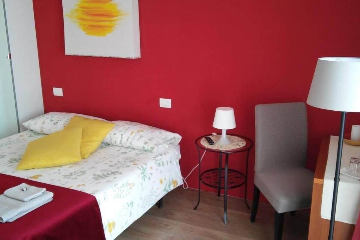 Et hotelværelse med en seng, en stol, en lampe og et lille bord.