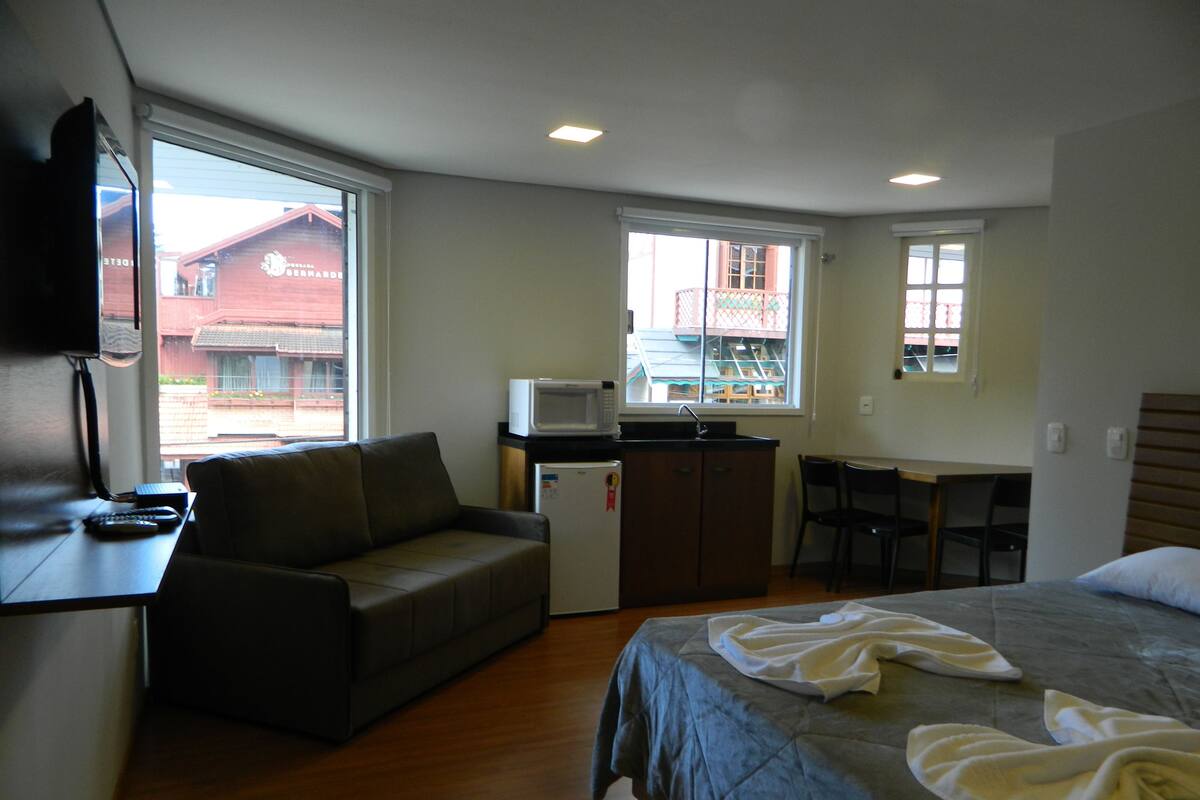 Une chambre d’hôtel compacte comprenant un lit, une petite kitchenette, un canapé et un bureau.