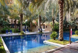 A swimming pool with lounge chairs and palm trees.