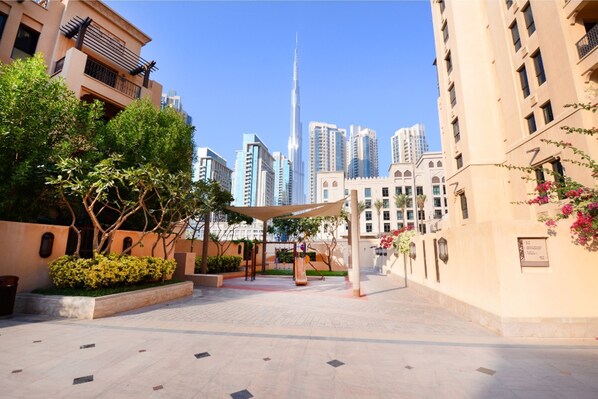A courtyard with a playground, surrounded by buildings with balconies and a view of the Burj Khalifa.