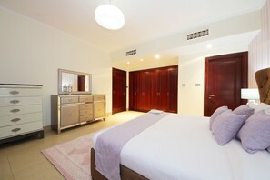 A bedroom with a bed, dresser, mirror, wardrobe, and a light fixture.