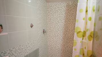 Un bagno con due servizi igienici, un lavandino, una doccia e uno sgabello.