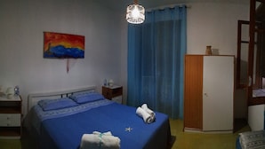 Ein Schlafzimmer mit Bett, Nachttisch, Kleiderschrank, einem Gemälde und einer Pendelleuchte.