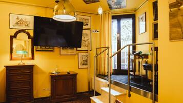 Une chambre d’hôtel équipée d’un lit, d’un bureau, d’une chaise, d’une télévision et d’un escalier menant à une autre pièce.