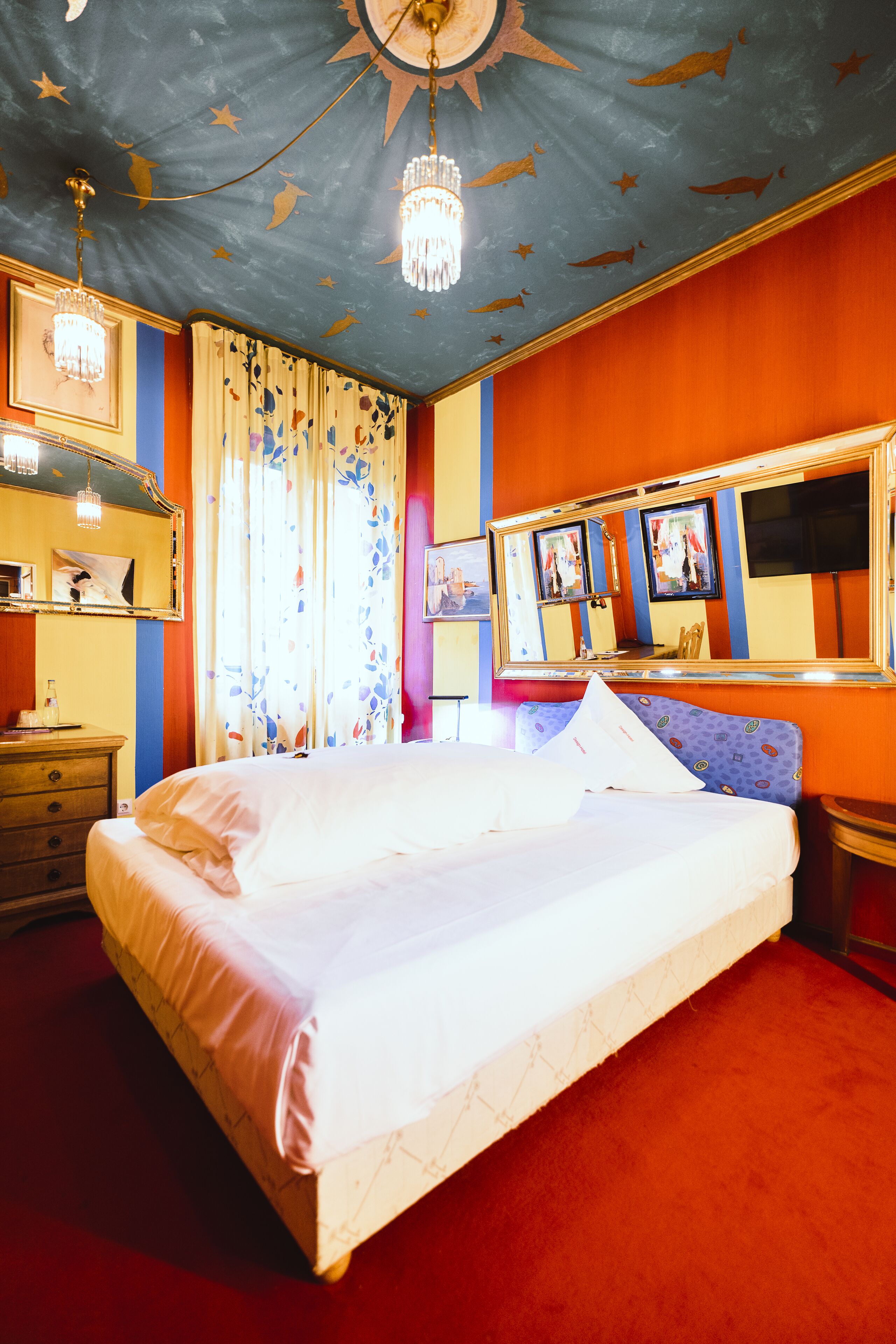 Un dormitorio con cama, cómoda, espejo y candelabro.