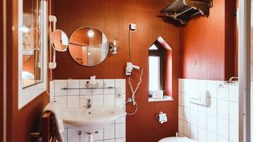 Ein kleines Badezimmer mit Waschbecken, Spiegel und zwei Toiletten.