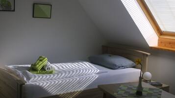 A bedroom with a bed, a nightstand, a vase with a flower, and a skylight.