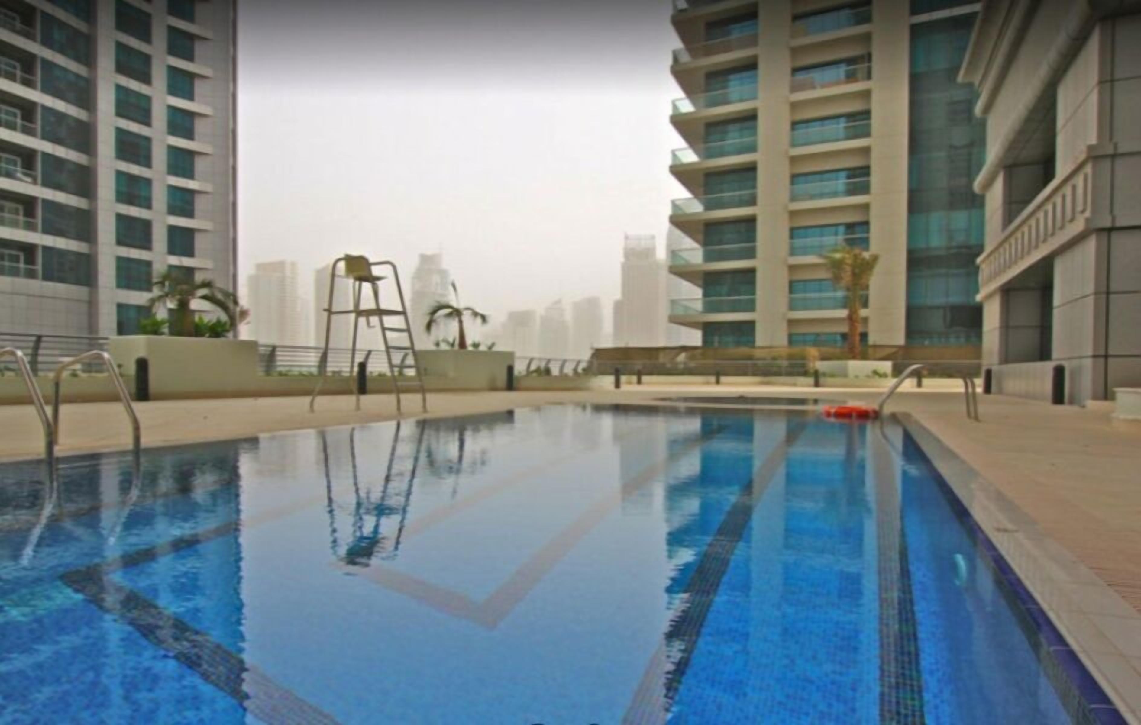A swimming pool with clear blue water, surrounded by modern buildings.