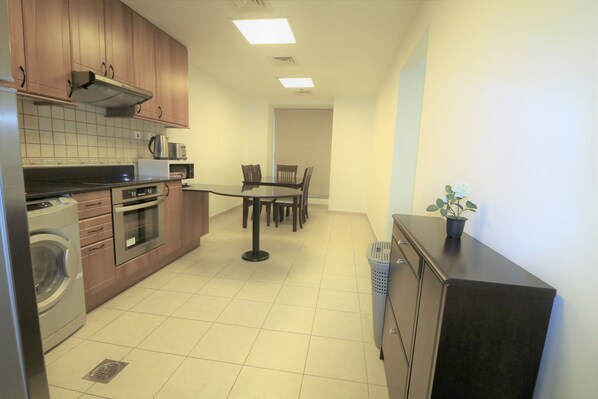 A compact kitchen with a dining area, built-in appliances, and a potted plant.