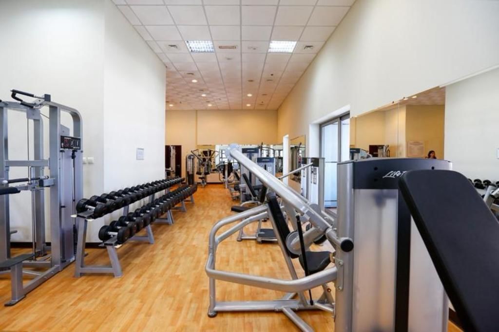 Un gimnasio con diverso equipo de ejercicio, como mancuernas, máquinas de pesas y cintas de correr.