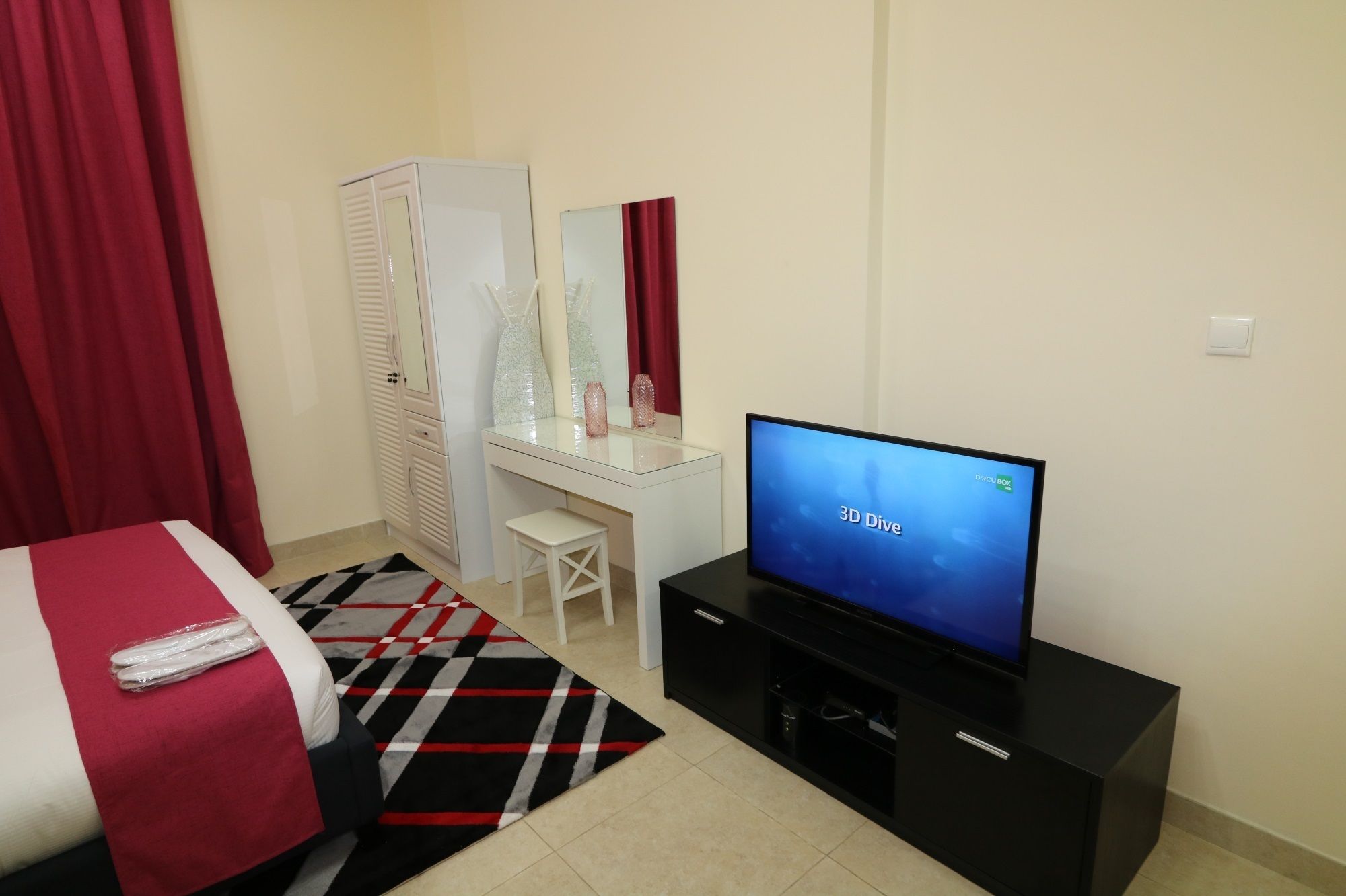 A hotel room with a bed, a desk, a TV, and a wardrobe.