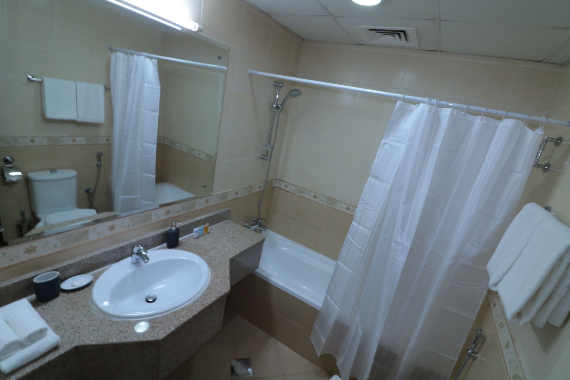 A bathroom with a sink, mirror, toilet, shower, and bathtub.