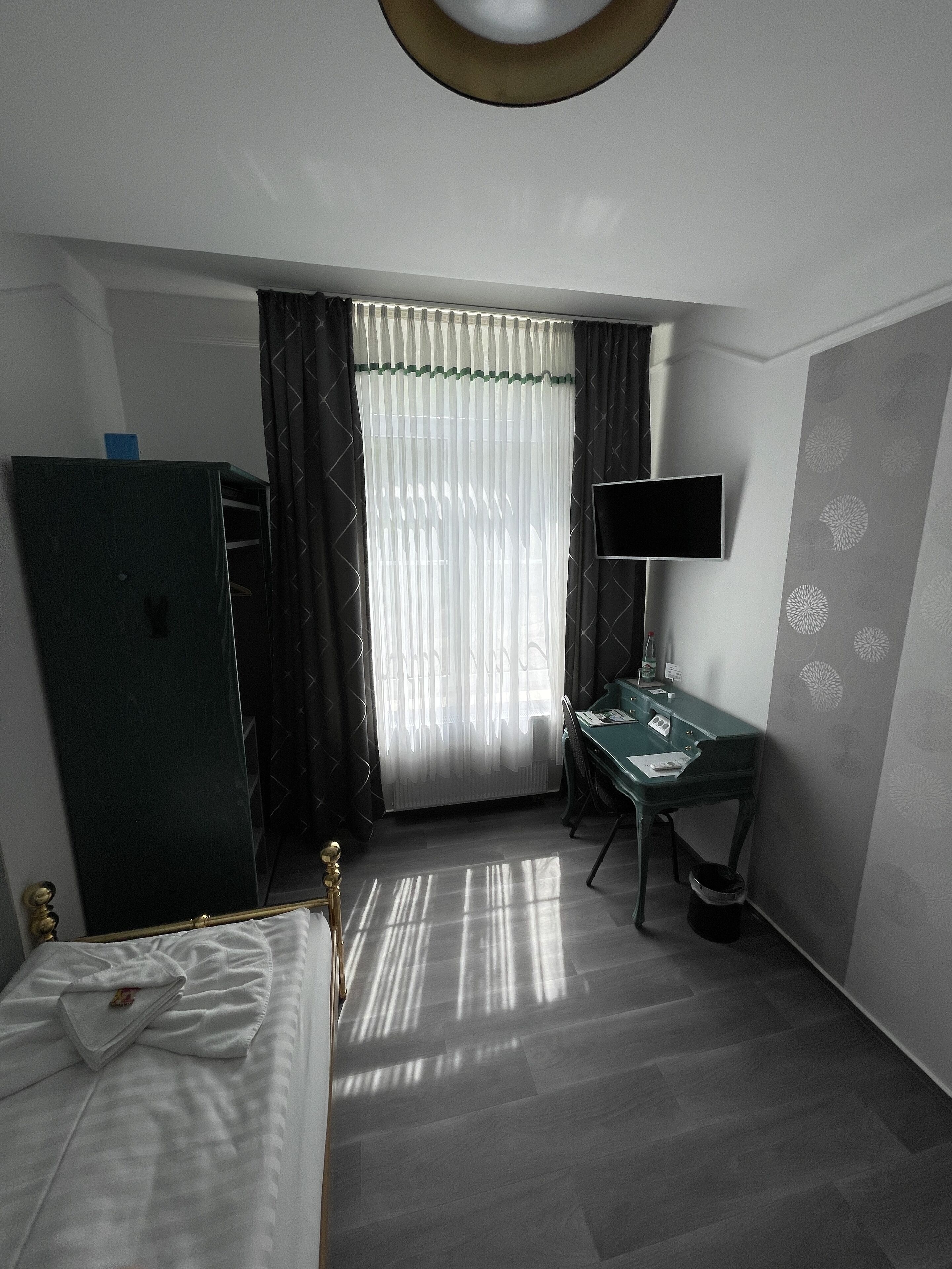Une chambre d’hôtel équipée d’un lit, d’un bureau, d’une télévision et d’une armoire.