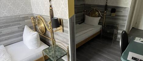A modern hotel room with two beds, a marble-topped table, and a green chair.