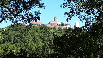 A historic building with a prominent tower, surrounded by dense greenery.