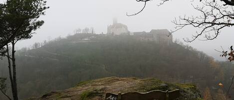 Un banco sobre un promontorio rocoso con vistas a un paisaje brumoso y un edificio a lo lejos.