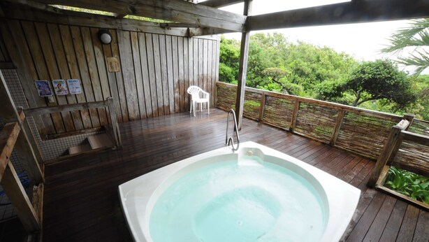 A wooden deck with a hot tub, a white chair, and a wooden fence overlooking a lush green landscape. - HOTEL Akenohoshi (Muroto)