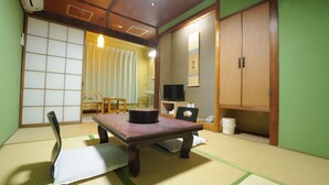 A traditional Japanese room with tatami flooring, a low table, a television, and sliding doors. - HOTEL Akenohoshi (Muroto)