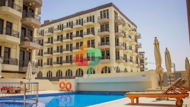 Un hotel con piscina, varios balcones y tumbonas.