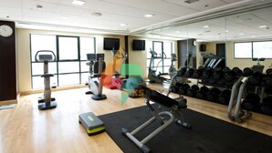 Un gimnasio con máquinas de cardio, bancos de pesas y mancuernas.