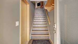 A staircase with a wooden handrail, a door on the left, and a window on the right. - 732b Meadow Creek 2 Bedroom Townhouse by RedAwning (Frisco)
