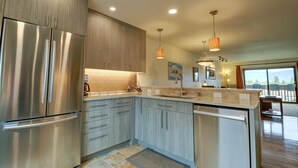 A modern kitchen with stainless steel appliances, wooden cabinets, and pendant lighting. - 732b Meadow Creek 2 Bedroom Townhouse by RedAwning (Frisco)