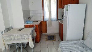 Cocina compacta con una mesa de comedor, un refrigerador y un lavamanos pequeño.