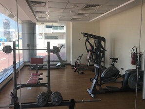 A gym with various exercise equipment, including a bench press, weight rack, and cardio machines. - Piks Key - Cricket Tower Sports City (Dubai)