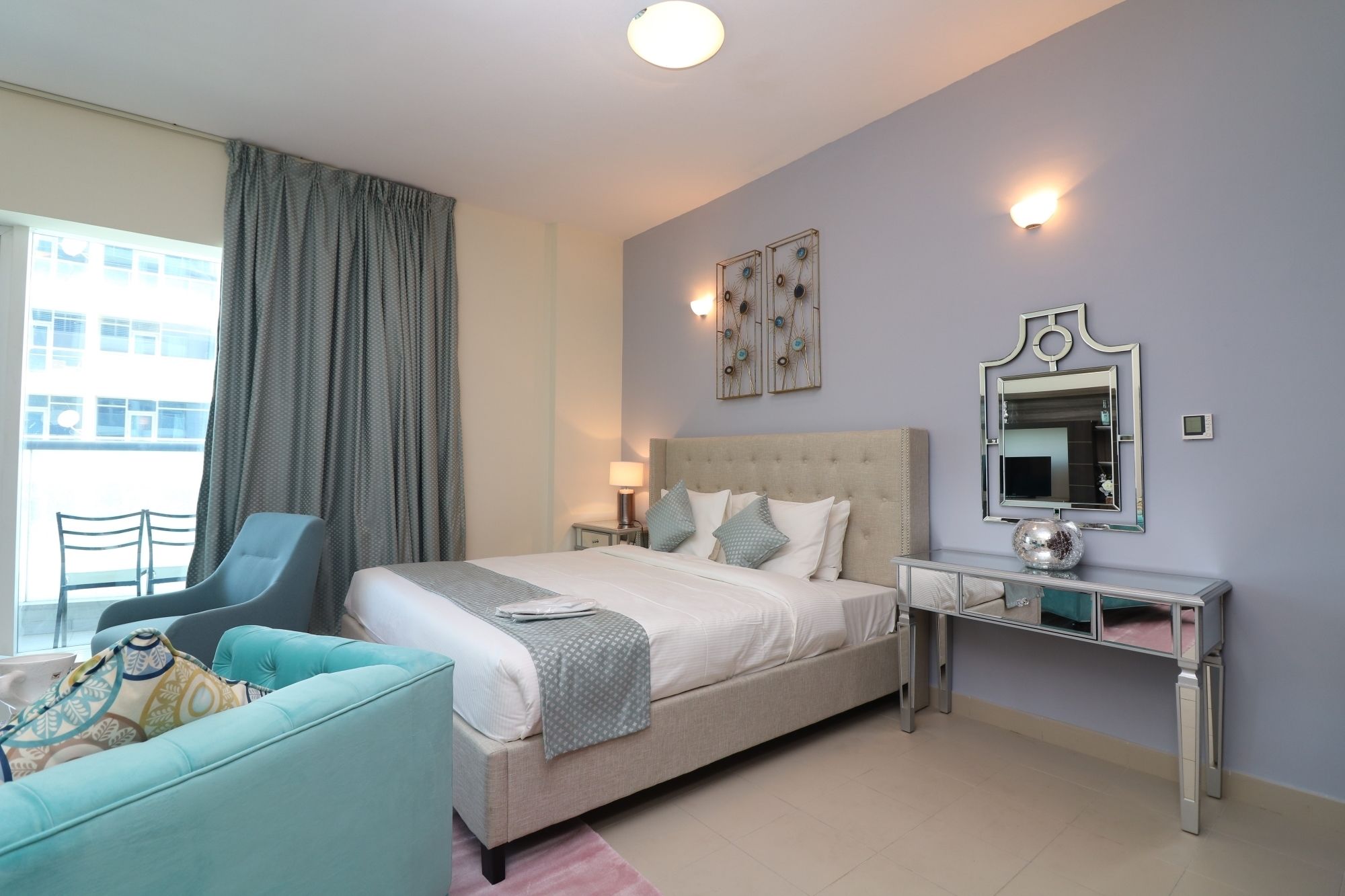 Una habitación de hotel moderna con una cama grande, una mesita de noche, una silla y vistas a la ciudad.