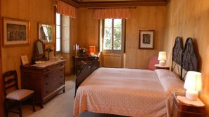 Una stanza in legno con un letto, una cassettiera, una sedia e due lampade.